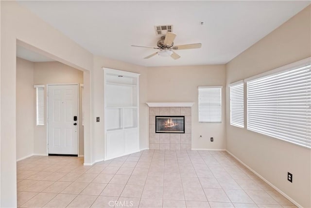 unfurnished living room with ceiling fan, a tile fireplace, and light tile patterned flooring