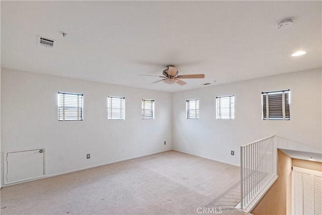 empty room with ceiling fan, plenty of natural light, and light colored carpet