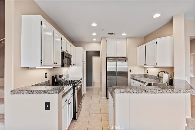 kitchen with kitchen peninsula, light tile patterned floors, white cabinetry, appliances with stainless steel finishes, and sink