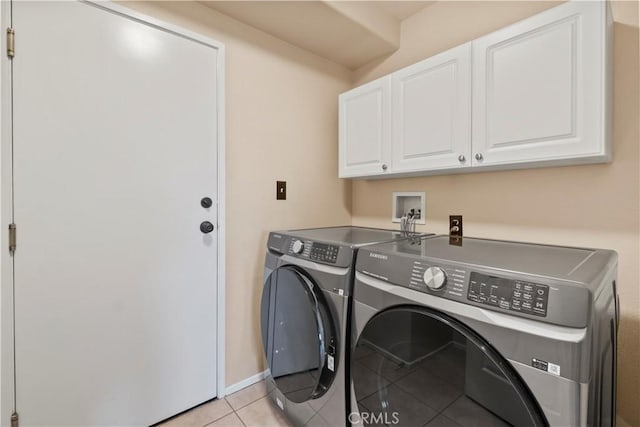 laundry area featuring separate washer and dryer, cabinets, and light tile patterned floors