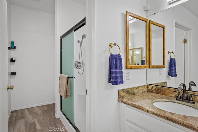 bathroom with hardwood / wood-style floors, walk in shower, and vanity