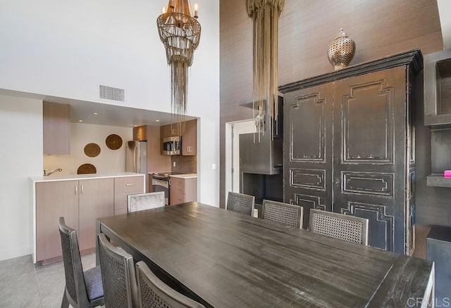 tiled dining area featuring a high ceiling and a chandelier