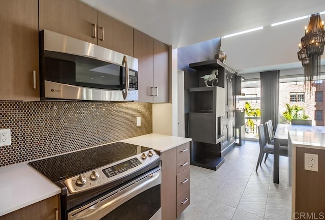 kitchen with stainless steel appliances, light tile patterned flooring, decorative backsplash, and a chandelier