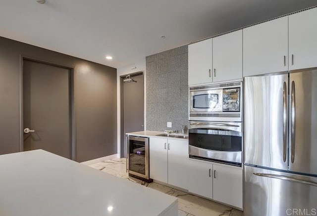 kitchen with sink, stainless steel appliances, beverage cooler, and white cabinetry