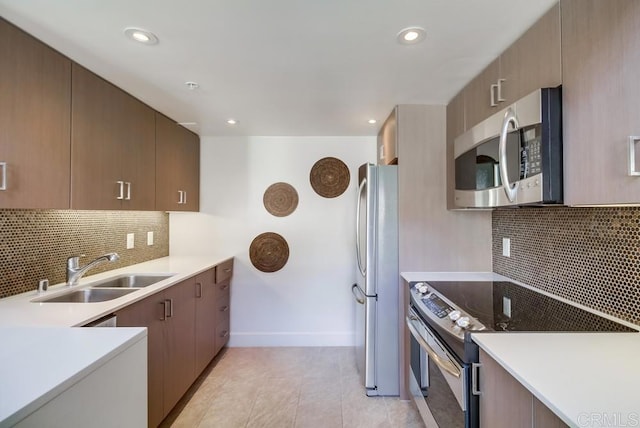 kitchen with stainless steel appliances, decorative backsplash, sink, and light tile patterned floors