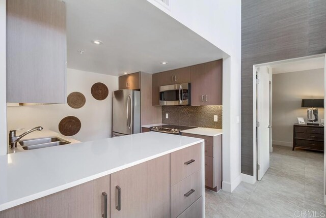 kitchen with kitchen peninsula, stainless steel appliances, tasteful backsplash, and sink