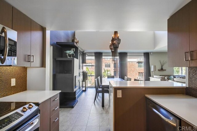 kitchen with appliances with stainless steel finishes, light tile patterned flooring, decorative backsplash, and dark brown cabinetry