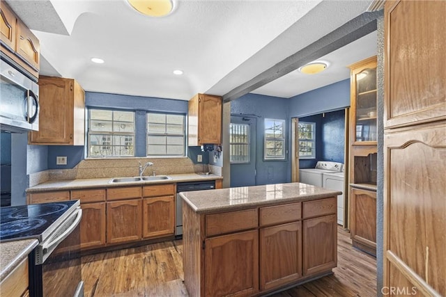 kitchen featuring appliances with stainless steel finishes, sink, dark wood-type flooring, independent washer and dryer, and a center island