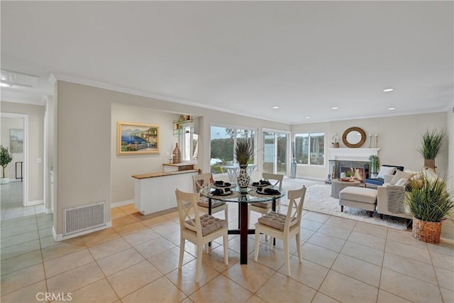 tiled dining space with ornamental molding and a fireplace