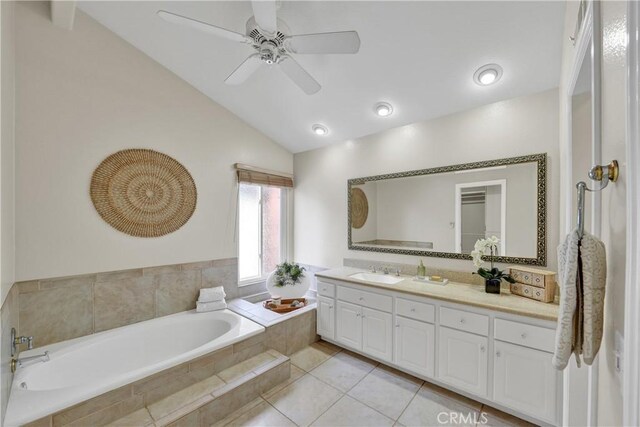 bathroom featuring tile patterned floors, lofted ceiling, vanity, a relaxing tiled tub, and ceiling fan