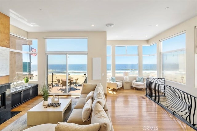 sunroom featuring a water view, plenty of natural light, and a view of the beach