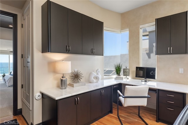 kitchen featuring built in desk, light hardwood / wood-style floors, and dark brown cabinets