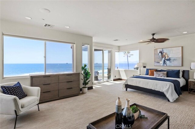 carpeted bedroom with access to exterior, ceiling fan, and a water view