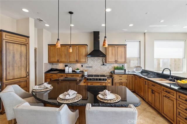 kitchen with pendant lighting, sink, a center island, tasteful backsplash, and wall chimney exhaust hood