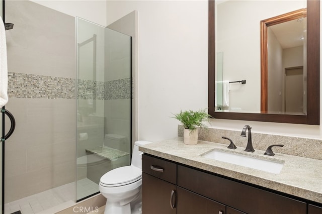 bathroom with vanity, a shower with door, and toilet