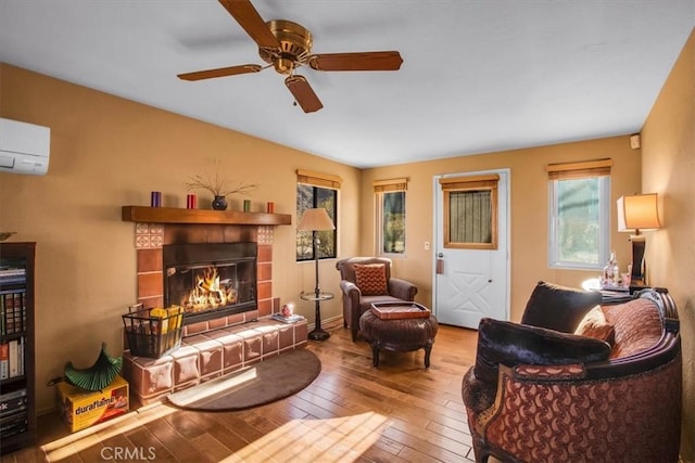 living room with a fireplace, hardwood / wood-style floors, ceiling fan, and a wall mounted air conditioner