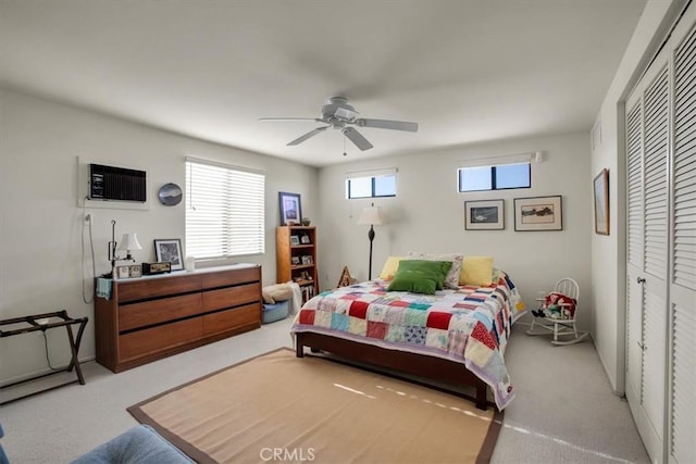 carpeted bedroom featuring ceiling fan, a wall mounted AC, and a closet