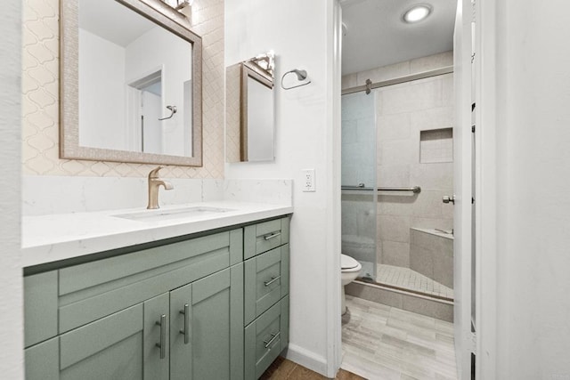 bathroom with toilet, a shower with door, and vanity