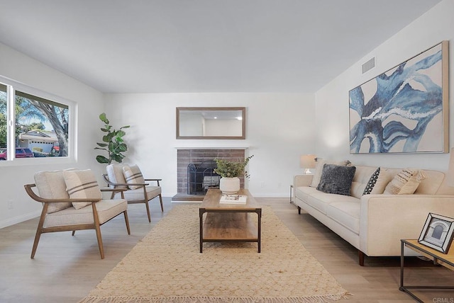 living room featuring a tile fireplace and light hardwood / wood-style flooring