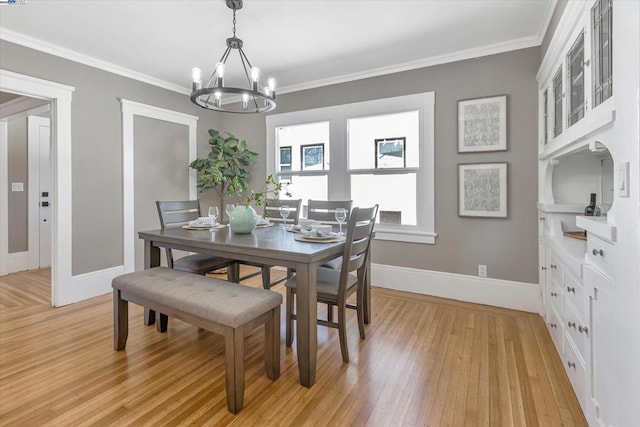 dining space with an inviting chandelier, ornamental molding, and light hardwood / wood-style floors