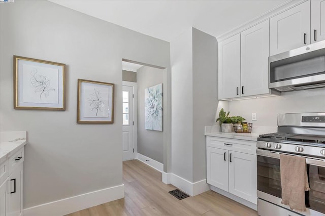 kitchen featuring light hardwood / wood-style floors, stainless steel appliances, white cabinetry, and light stone countertops