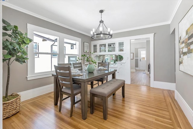 dining area with a chandelier, ornamental molding, and light hardwood / wood-style flooring