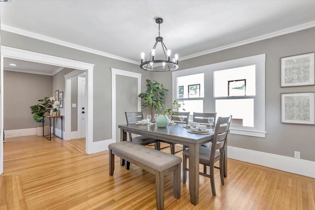 dining space featuring a notable chandelier, light wood-type flooring, and crown molding