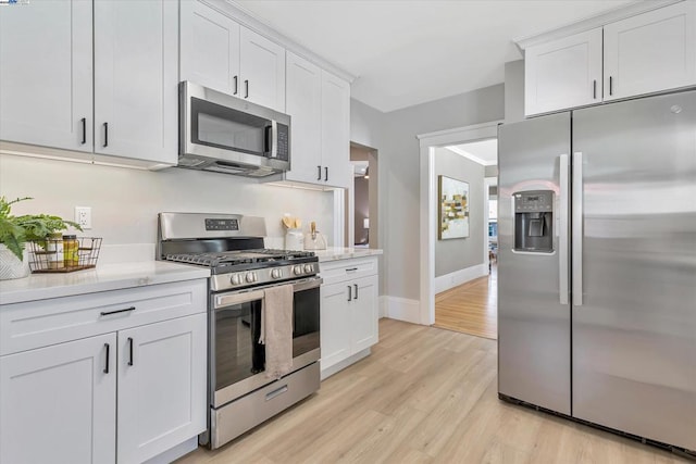 kitchen featuring white cabinets, light stone counters, light hardwood / wood-style flooring, and appliances with stainless steel finishes