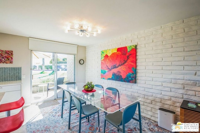 dining room with brick wall and an inviting chandelier