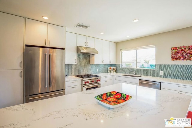 kitchen with white cabinets, light stone counters, and high quality appliances