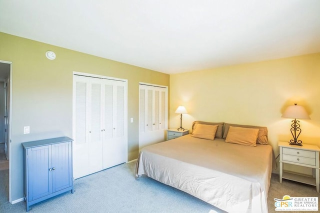 bedroom with multiple closets and light carpet