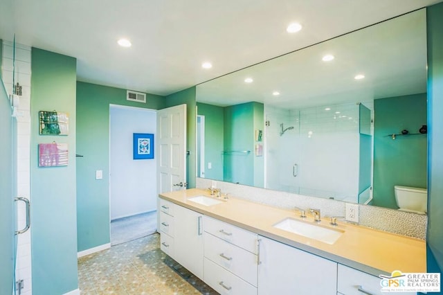 bathroom with toilet, vanity, and a shower with shower door