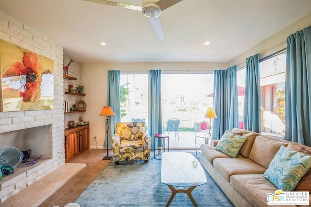 living room featuring a brick fireplace, ceiling fan, and light tile patterned floors