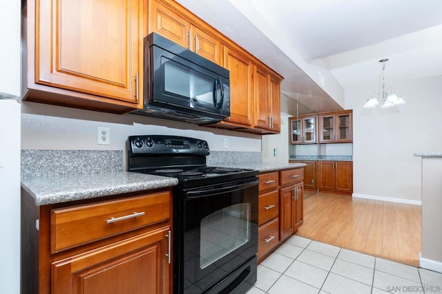 kitchen featuring decorative light fixtures, light tile patterned floors, black appliances, and a chandelier