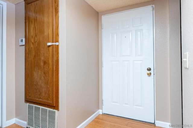 entryway featuring a textured ceiling and light hardwood / wood-style flooring