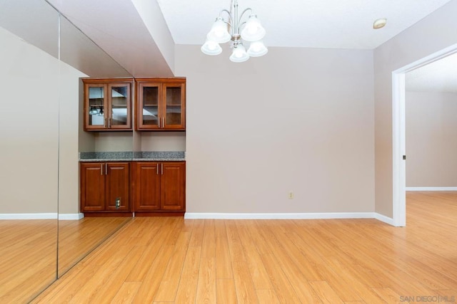 unfurnished dining area with a notable chandelier and light hardwood / wood-style flooring