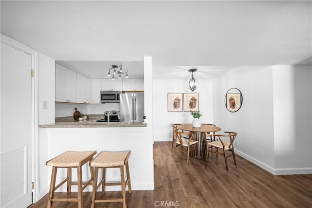 kitchen featuring decorative light fixtures, sink, white cabinets, kitchen peninsula, and stainless steel appliances