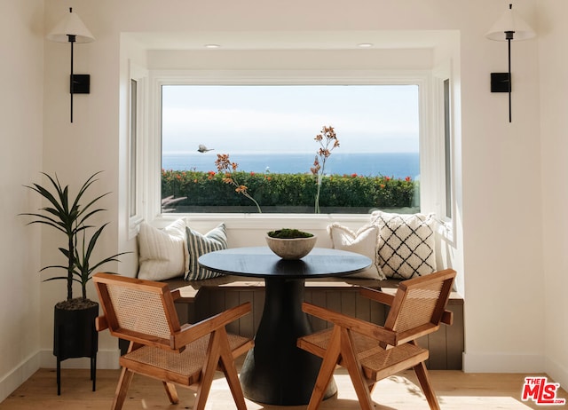 dining room featuring a water view, light wood-type flooring, and breakfast area