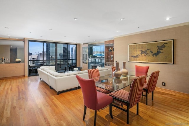 dining room with floor to ceiling windows, light hardwood / wood-style floors, and crown molding