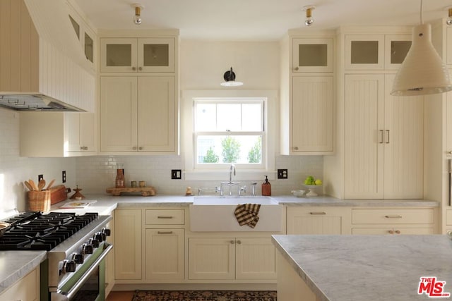 kitchen featuring custom exhaust hood, hanging light fixtures, stainless steel range, backsplash, and sink