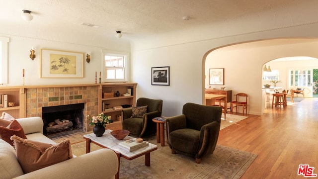 living room with a textured ceiling, light hardwood / wood-style flooring, and a fireplace