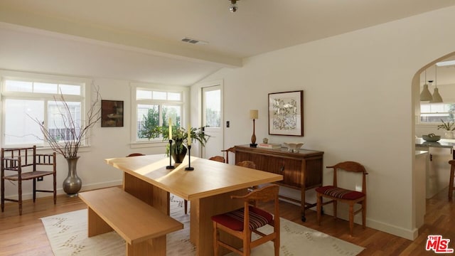 dining space featuring lofted ceiling with beams and hardwood / wood-style floors