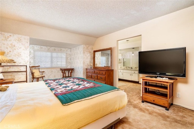 carpeted bedroom featuring a textured ceiling, ensuite bathroom, and lofted ceiling