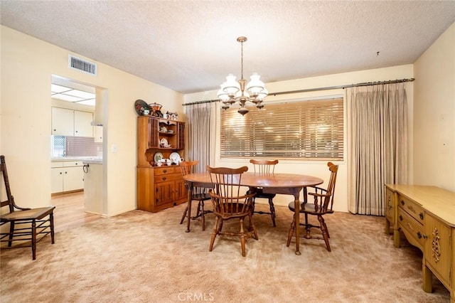 carpeted dining space with a notable chandelier and a textured ceiling