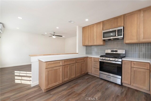 kitchen featuring appliances with stainless steel finishes, dark hardwood / wood-style flooring, kitchen peninsula, and backsplash