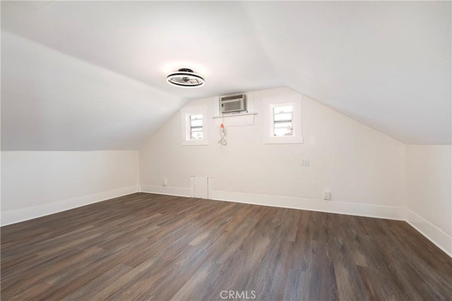 additional living space featuring lofted ceiling, dark hardwood / wood-style floors, and a wall unit AC