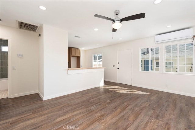 unfurnished room featuring a wall unit AC, dark hardwood / wood-style floors, and ceiling fan