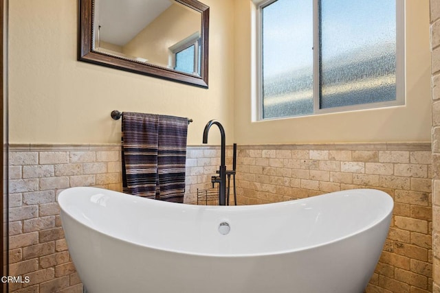 bathroom featuring tile walls, a tub to relax in, and sink