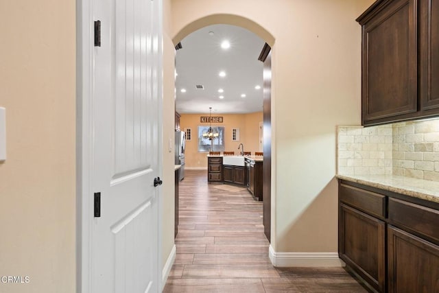 corridor with sink, an inviting chandelier, and hardwood / wood-style floors