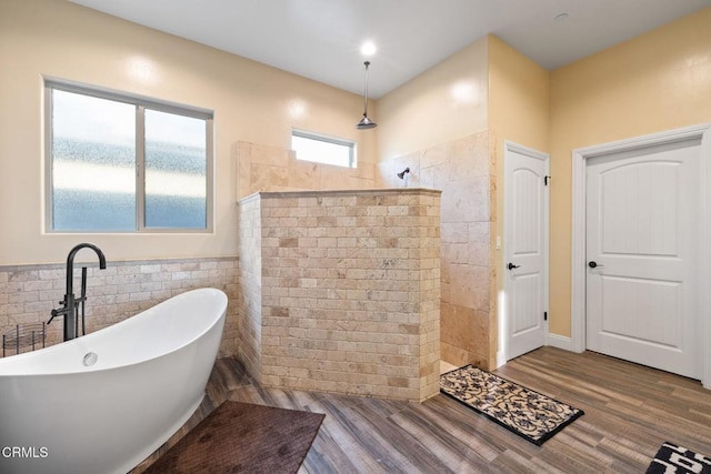 bathroom featuring tile walls, hardwood / wood-style flooring, and shower with separate bathtub